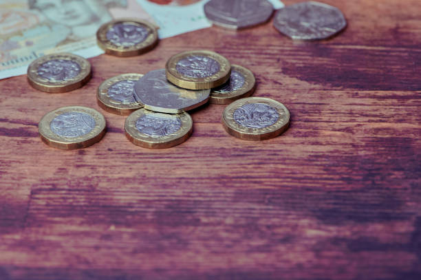 British one pound coins on wooden background stock photo