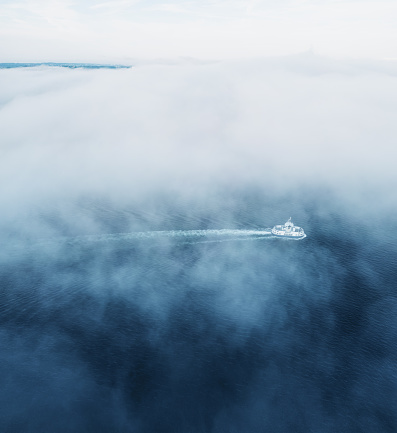 A public transit ferry navigates a harbour shrouded in fog.