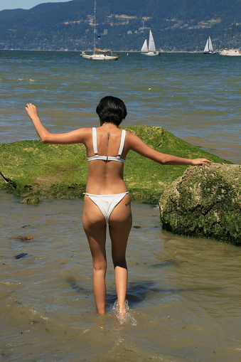 A Mexican woman wading to deeper water in the Pacific Ocean. She is wearing a white bikini.