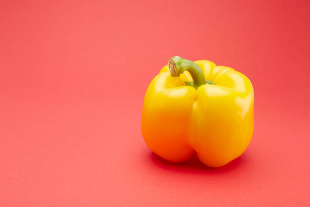 Close up of yellow bell pepper isolated on red background.