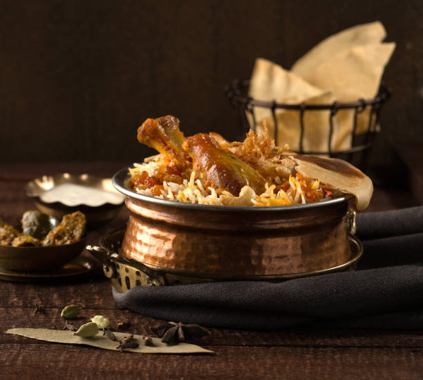Chicken biriyani with raita and pickle served in a golden dish isolated on dark background side view stock photo