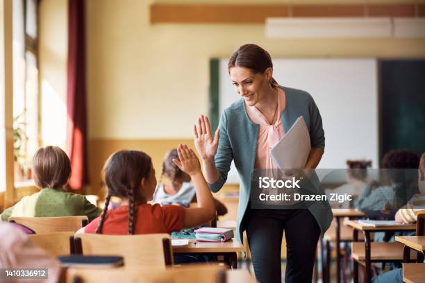 Happy Teacher And Schoolgirl Giving High Five During Class At School Stock Photo - Download Image Now
