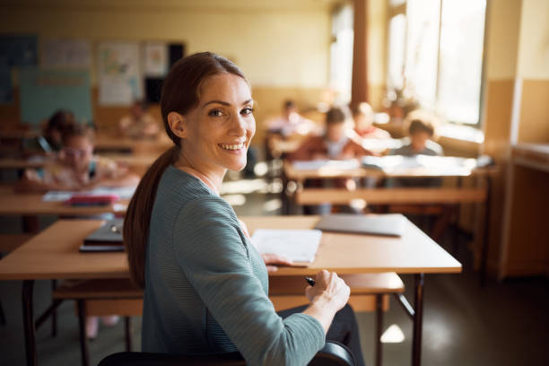 istock Happy female teacher in the classroom looking at camera. 1410337531