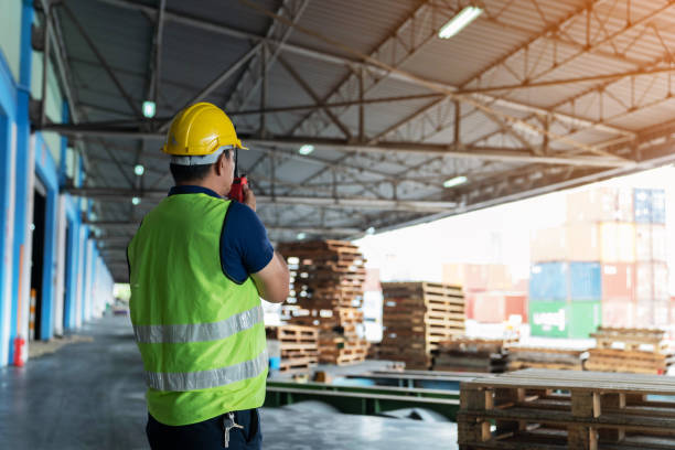 istock the caucasian engineer using walky talky comunicate with lifting container team with blue sky. Logistics transportation industry forklift handling container box loading stacker. back side worker view. 1410337817