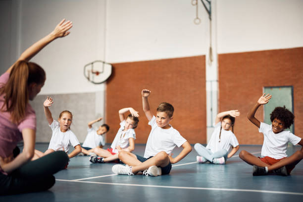 istock Elementary school children exercising with PE teacher at school gym. 1410337883