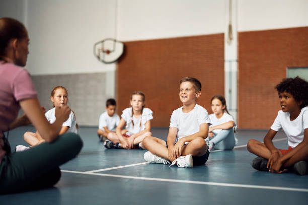 istock Happy elementary student and his classmates having PE class with female coach at school gym. 1410337888