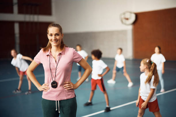 istock Happy female coach during PE class at school gym and looking at camera. 1410337964