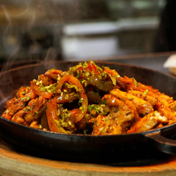 mexican food, chicken fajitas serving on a hot smoking sizzling plate in close up