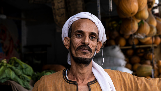 Hurghada, Egypt - December 13, 2021: close-up of authentic Arab Men in turban pumpkins seller on the farmers market