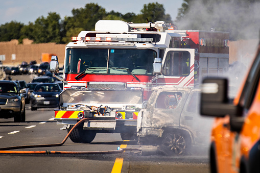 Burned out car road accident with fire truck on highway