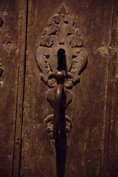 Old carved wooden door of a church with an old lock in a French village