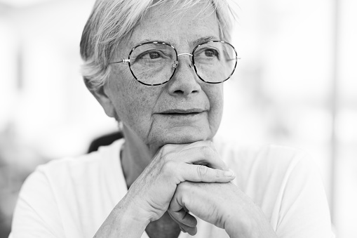 Black and white portrait of a beautiful senior Caucasian woman with eyeglasses as she looks thoughtfully away
