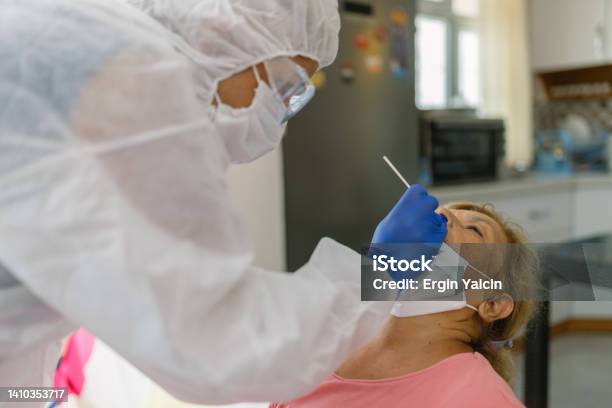 Doctor In Protective Workwear Taking Nose Swab Test From Senior Woman At Home Stock Photo - Download Image Now