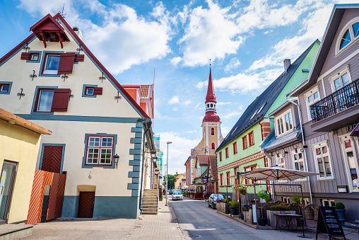 Parnu, Estonia - August 6, 2019: A street lined with wooden buildings in central Pärnu. In the background is the 18th century St Elizabet's Church, a landmark in the city.