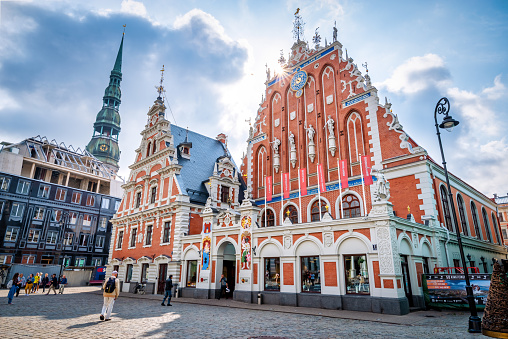 Riga, Latvia - August 7, 2019: View of the Old Town Ratslaukums square, Roland Statue, The Blackheads House near St Peters Cathedral against blue sky in Riga, Latvia. Summer sunny day.