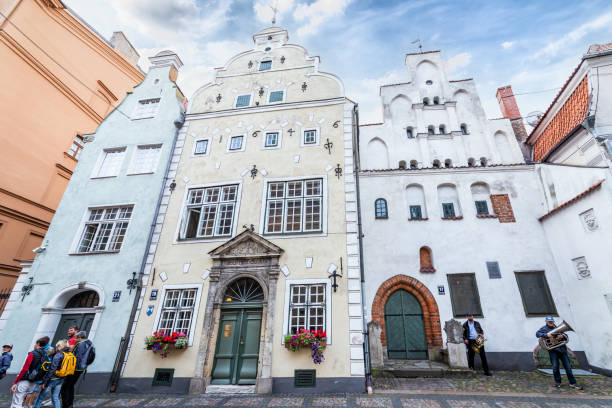 Riga, Latvia - August 7, 2019: View in the famous three brothers houses with group of tourists in the old town of Riga. It is the oldest complex of dwelling houses in Riga