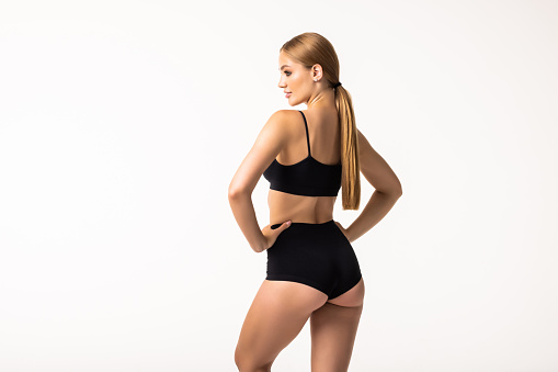 Well-kept skin, perfect buttocks. Back view of beautiful body of young caucasian woman in black lingerie isolated on gray studio background. Natural beauty, treatment, fitness and diet concept. Flyer