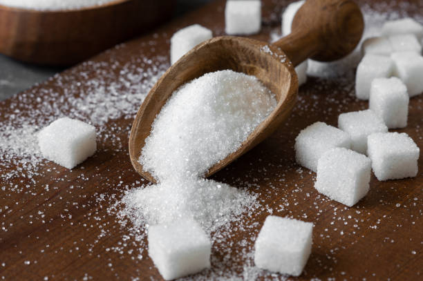 istock Heap of white granulated sugar in spoon and bowl with sugar cube 1410356447