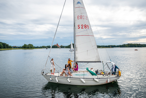 Trakai, Lithuania - August 10, 2019: people in a boat enjoying the day at Galve Lake,  near Trakai old red bricks castle. Trakai Castle is one of the most popular tourist destinations in Lithuania.