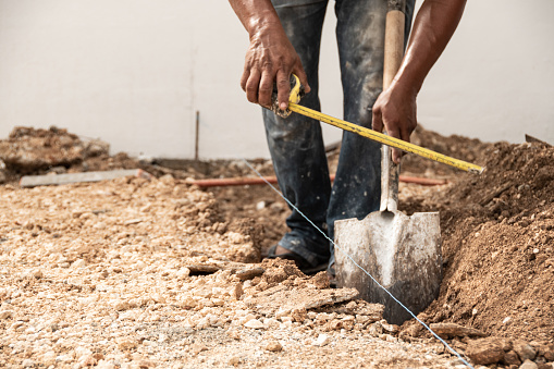 Man measuring and digging a hole in the ground with shovel