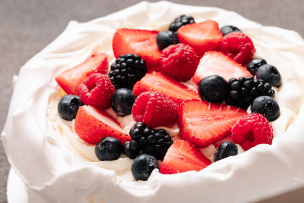 istock Pavlova meringue cake with fresh berries on brown background 1410358645