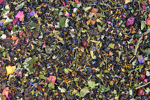 Texture of dry black tea mixed with herbs, leaves and dried berries. Mixed herbal vitamin tea background.