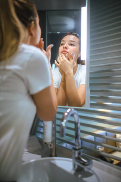 istock Woman moisturizing face in the bathroom. 1410366536