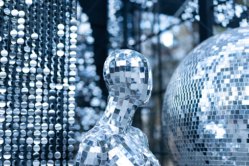Male mannequin covered with slices of a mirror on a black background mr disco. a super cool disco club character against sparkling background