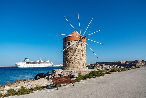 One windmill at Mandraki Harbor in Rhodes Island - Greece. In the background, the cruise anchored in the harbor is visible.