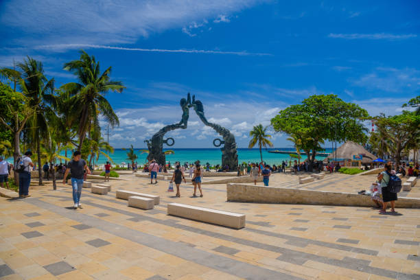 visitantes se misturam na praia do parque fundadores, na praia de playa del carmen, na costa caribenha da riviera maya, com artistas sob a escultura do portal maya - beach tourist resort mexico tropical climate - fotografias e filmes do acervo