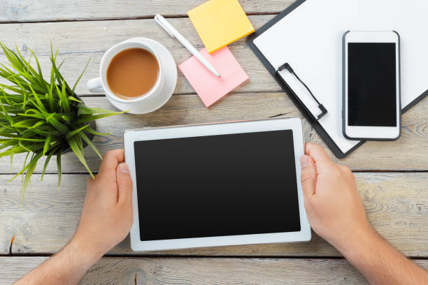 istock hands of a man holding blank tablet device over a wooden workspace table 1410373990