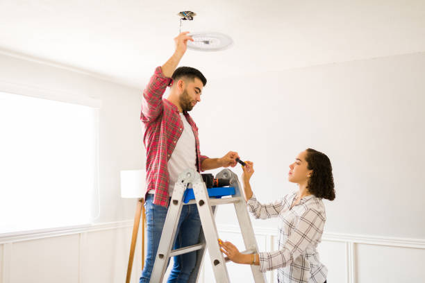 Young handy man repairing a new lamp on the ceiling