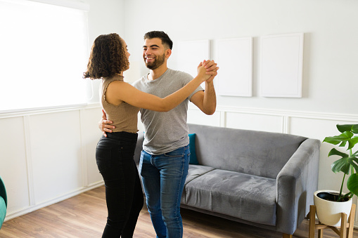 Attractive caucasian couple dancing in the living room and feeling in love while enjoying their beautiful home