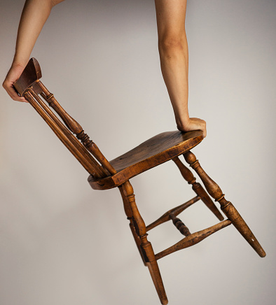 Asian Male Handstand Balancing on one leg of a simple wooden asian chair