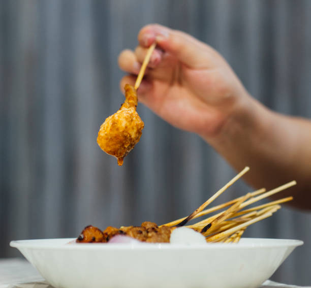 istock Satay on stick with rice hand holding ketupat 1410390097
