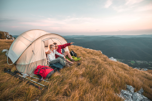 Romantic senior couple hugging and enjoying a breathtaking view of a valley. They are camping in the countryside.