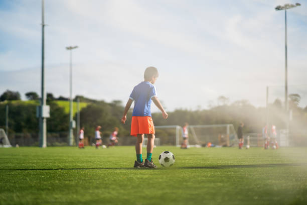 A young toddler runs off with the soccer ball. 