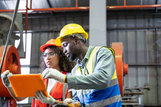 istock African mechanical engineer, wearing safety equipment. While doing machine maintenance and safety control while work inside of factory area. With blurred background of heavy machine. Success team. 1410395756