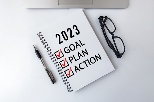 Objetivo 2023, Plan, Texto de la lista de verificación de acción en el bloc de notas con computadora portátil, gafas y bolígrafo. photo