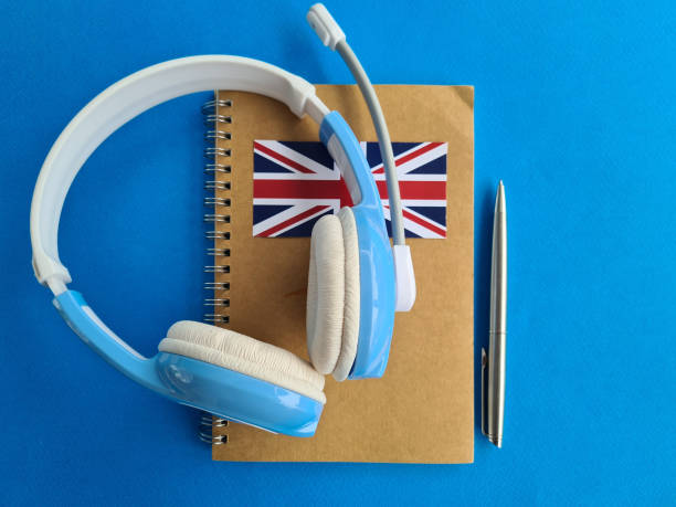 istock Notepad with British flag pen and headphones on blue background. 1410402215