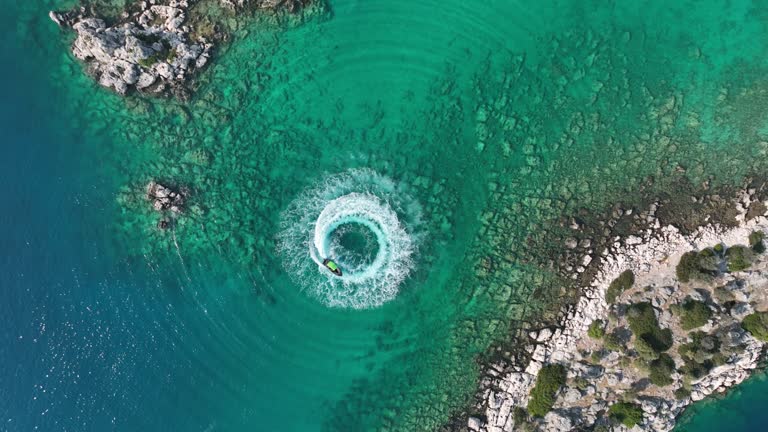 4K zoom out amazing aerial view of man driving a personal watercraft in the ocean creating a straight down circular pattern,Amazing summer background, Water color and beautiful bright Clear turquoise Adventure day on tropical beach, Spinning speed boat