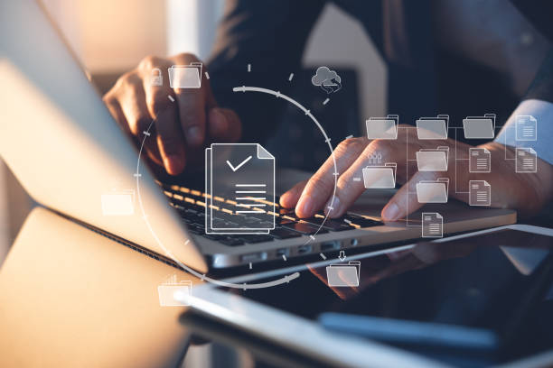 el sistema de gestión de documentos (dms) está siendo configurado por un consultor de ti que trabaja en una computadora portátil en la oficina. software para archivar, buscar y gestionar archivos corporativos - telephone directory fotografías e imágenes de stock