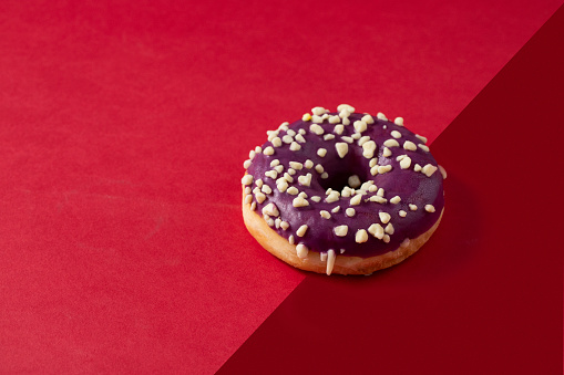 Blueberry glaze donut with nuts  topping on two colour background