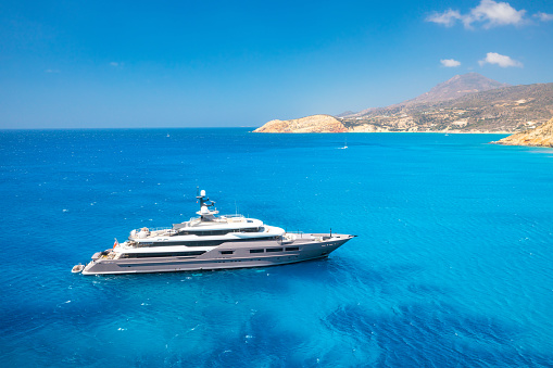Multideck yacht in a bay with azure water. Summer holidays and trips on the ship. Aerial view of marine transportation. Luxury life. Summer vacation time. Seascape from the drone.