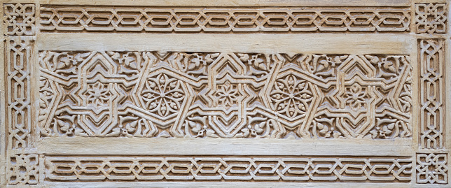 Tiles with bas-relief of Arabic and Mudejar style on a wall of the Alcaicería of Granada, Spain
