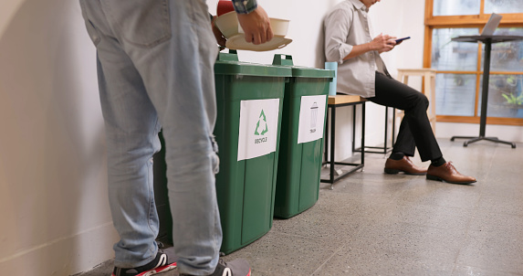 Waste separation and environmental friendly in business office - close up of Man throwing paper container into recycling bin