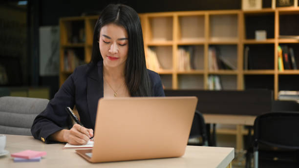 istock Executive asian businesswoman using laptop computer and writing her business plan on notebook. 1410418867