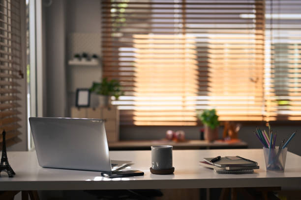istock Contemporary home office. Computer laptop, coffee cup, notebooks and pencil holder on white table. 1410419495