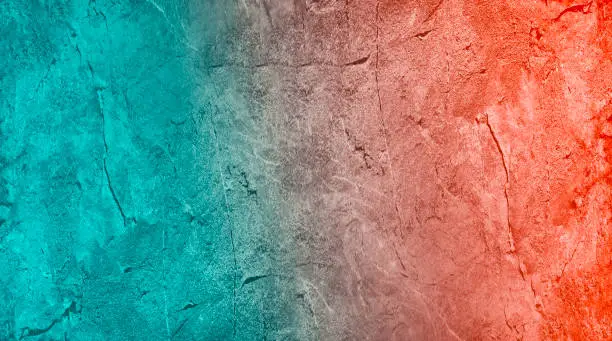 Photo of Dark orange blue green teal abstract background. Gradient. Toned rough stone surface with cracks. Close-up.