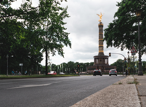The Victory Column (Siegessäule) is an old monument in Berlin. In the foreground is a street leading towards it.